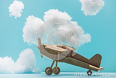 Wooden toy plane among white fluffy clouds made of cotton wool isolated on blue Stock Photo