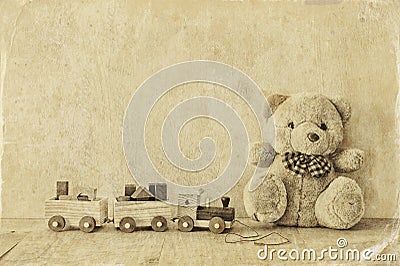Wooden toy train and teddy bear over wooden floor. black and white style photo Stock Photo