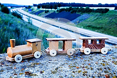 Wooden toy train on wall above a freeway Stock Photo
