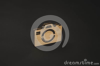 Wooden trinket in the form of a camera on a black background. keychain Stock Photo