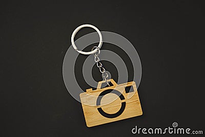 Wooden trinket in the form of a camera on a black background. keychain Stock Photo