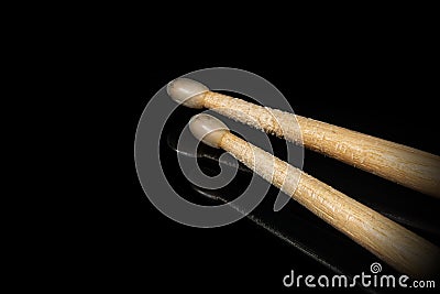 Wooden used drumsticks on a black background with reflections Stock Photo
