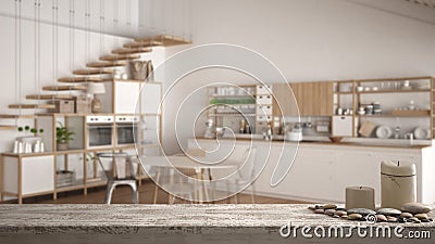 Wooden vintage table top or shelf with candles and pebbles, zen mood, over blurred empty minimalist white wooden kitchen, loft wit Stock Photo