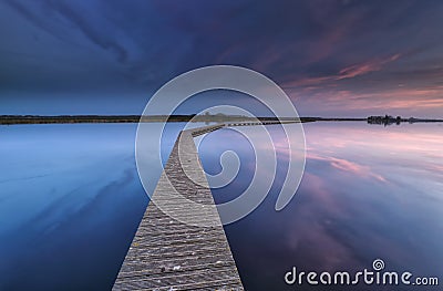 Wooden walkpath on water at dawn Stock Photo