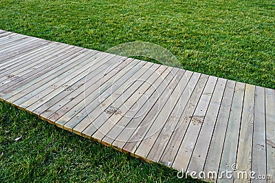 Wooden walking path on green grass. Stock Photo