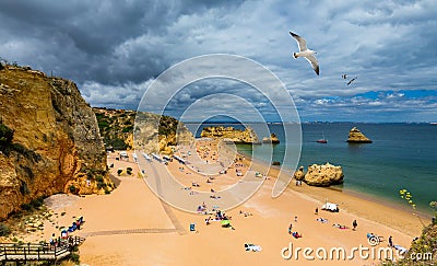 Wooden walkway to famous Praia Dona Ana beach with turquoise sea water and cliffs, flying seagulls over the beach, Portugal. Editorial Stock Photo