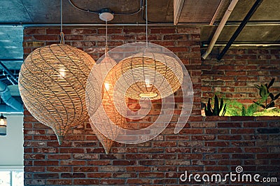 Wooden weave lamp hanging on ceiling and brick wall Stock Photo