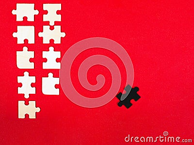 Wooden white and black puzzles on a red background outcast antisocial leader differ from others children educational toy Stock Photo