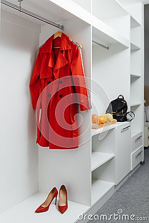Wooden white wardrobe for womenâ€™s clothes, open doors, decor, bag, hangers, silk dresses in a bright room, concept, flowers Stock Photo