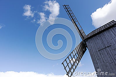 Wooden windmill wings on a background of blue sky and clouds Stock Photo