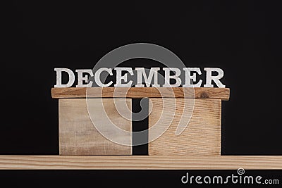 Wooden winter calendar months - December. Wooden letters. Black background Stock Photo