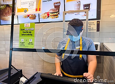 Woodland, CA,USA November 8 2022, Mc Donalds employee using a surgical mask taking an order at the restaurant cashier counter Editorial Stock Photo