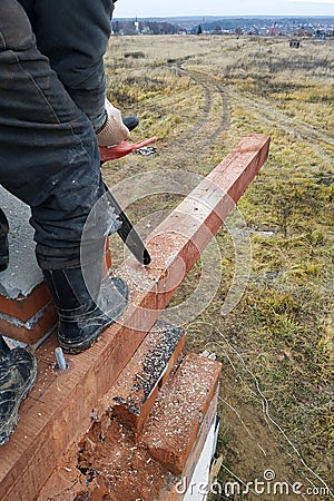 woodworker with a chainsaw makes drank on a wooden beam construction of houses Stock Photo