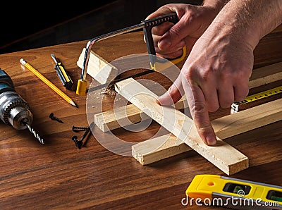 Woodworker sawing a wooden plank. Close up of a foreman hand at work. Working environment in a carpentry workshop Stock Photo