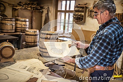 Woodworker shows drawing, according to which wooden barrels are to be built in a vintage workshop Stock Photo