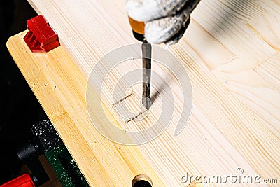 Woodworker using chisel cuts slot on wooden board Stock Photo