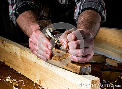 Woodworker using hand plane to clean up a wooden board. Hands of the master closeup at work. Working environment in carpentry Stock Photo