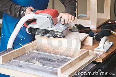 Woodworking entrepreneurs use sandpaper finishing machines to assemble and build wooden tables for their clients Stock Photo