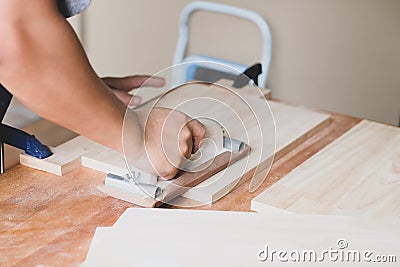 Woodworking entrepreneurs are using sandpaper to decorate wooden pieces to assemble and build wooden tables for their Stock Photo