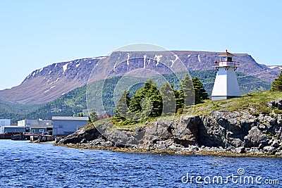 Woody Point Lighthouse along the shore of Bonne Bay with The Tablelands on the horizon Stock Photo
