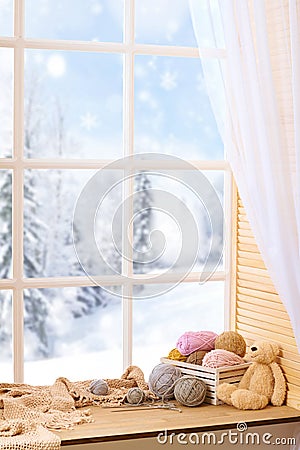 Woolen yarn and fabric on the window sill. Beautiful view outside the window - winter landscape and snow Stock Photo