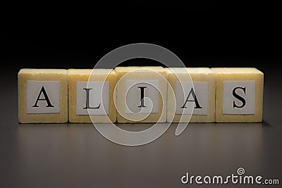 The word ALIAS written on wooden cubes isolated on a black background Stock Photo
