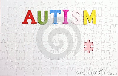 Word Autism on the background of the white puzzle. Autism Awareness Day Stock Photo