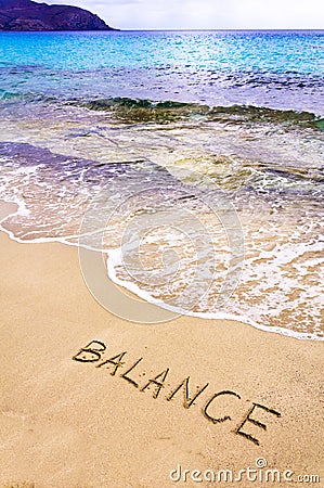 Word BALANCE written on beach sand, with sea waves in background Stock Photo