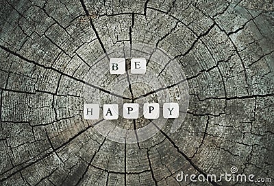 Word be happy of wooden beads on a tree stump surface in the forest. Stock Photo