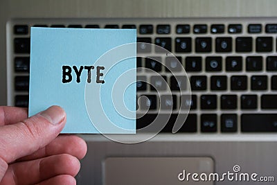 Word BYTE on sticky note hold in hand on keyboard background Stock Photo