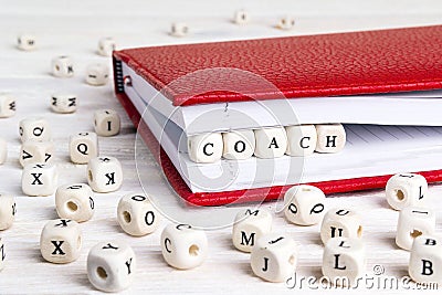 Word Coach written in wooden blocks in red notebook on white woo Stock Photo