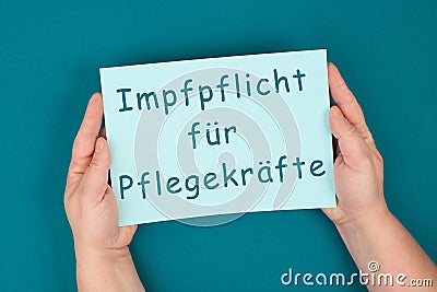 The word compulsory vaccination for caregivers is standing on the paper, german language, mandatory vaccine Stock Photo