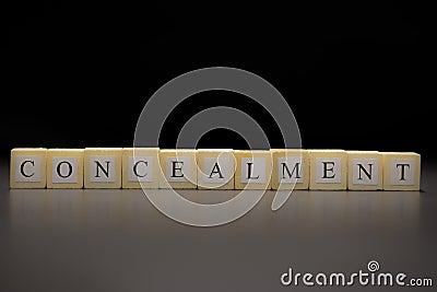 The word CONCEALMENT written on wooden cubes isolated on a black background Stock Photo