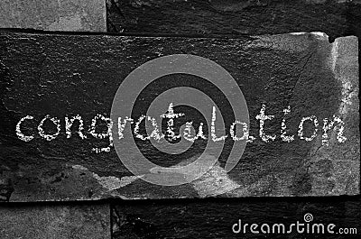 The word congratulation written with chalk on black stone. Stock Photo