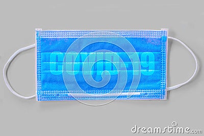 Word covid-19 on protective face mask flat lay on grey background, social distancing, corrona virus outbreak concept background Stock Photo
