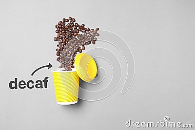 Word Decaf and arrow pointing at takeaway paper cup with coffee beans on light grey background, flat lay. Space for text Stock Photo