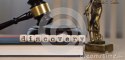 Word DISCOVERY composed of wooden dices. Wooden gavel and statue of Themis in the background Stock Photo