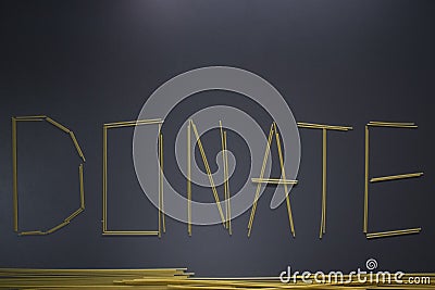 Word `donate` written with spaghetti on gray background, top view, copy space. Food supplies, donation on quarantine Stock Photo