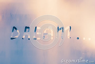 Word - dream... Abstract background with drops of water. Inscription on foggy window. Handwritten text on wet glass. Stock Photo