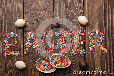 Word EASTER made of colorful sprinkles and chocolate eggs on wooden background Stock Photo