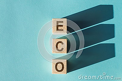 The word ECO on the wooden blocks with shadows on light blue background Stock Photo