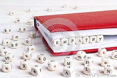 Word Empathy written in wooden blocks in red notebook on white w Stock Photo