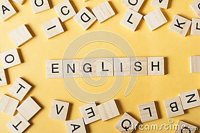 Word english made with block wood letters next to a pile of other letter over wooden table Stock Photo