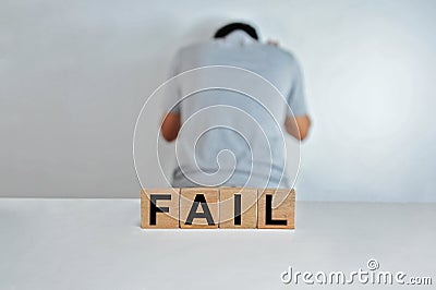 The word fail on wooden cubes, a person doing fail gesture on blur background, light wooden cubes signs, symbols signs Stock Photo