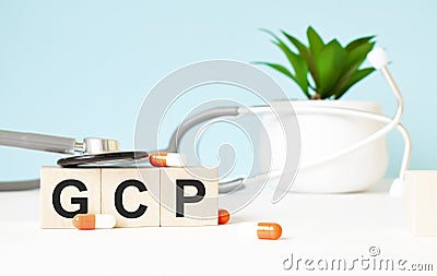 The word GCP is written on wooden cubes near a stethoscope on a wooden background. Medical concept Stock Photo