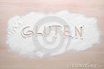 Word Gluten written with flour on wooden table, top view Stock Photo