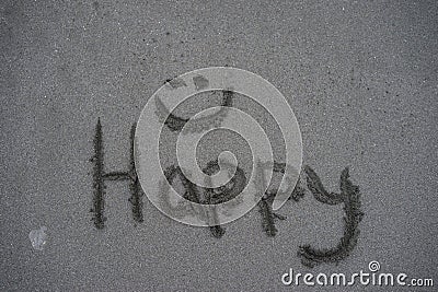 The word happy with a smilie face written in the sand Stock Photo