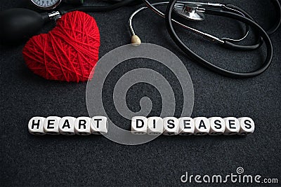 Word heart diseases from white cubes with letters on dark background with red thread heart and tonometer. Heart cardiovascular di Stock Photo