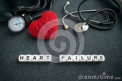 Word HEART FAILURE from white cubes with letters on dark background with red thread heart and tonometer. HEART FAILURE Stock Photo