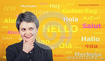 Word hello with different translations on the yellow wall. Multilingual woman learning and speaking many languages. International Stock Photo